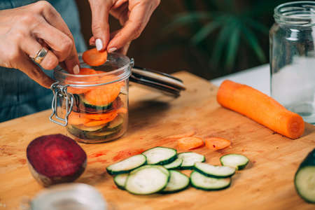 Fermentation process. Woman preparing vegetables for fermentation at home. Cutting cucumber and beets.の写真素材
