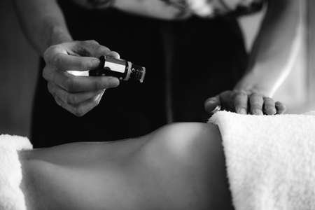 Ayurvedic therapist dropping ayurveda essential oil on female patient stomach