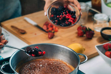 Fruit canning preservation. Woman cooking fruits and making homemade jam.の写真素材