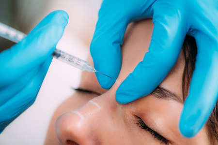 Dermal filler injection treatment. Doctor with surgical gloves injecting dermal filler into...