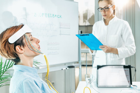 Biofeedback EEG or electroencephalograph training at a health center. Therapist monitoring brain waves using scalp sensors placed onto a clientâs headの写真素材