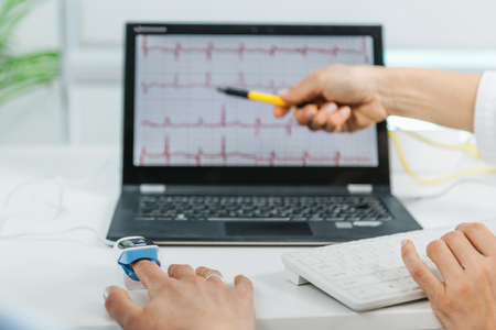 Biofeedback training session. Monitoring heart rate with a sensor attached to clientâs  finger. Therapist explaining heartrate patternsの写真素材