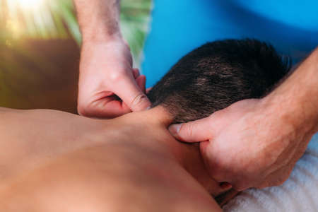 Physiotherapist massaging male patient with injured neck. Sports injury treatment.の写真素材