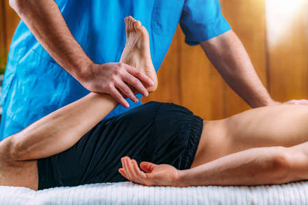 Physical therapist massaging injured leg of a male athlete. Sports injury physical therapy treatment.の写真素材