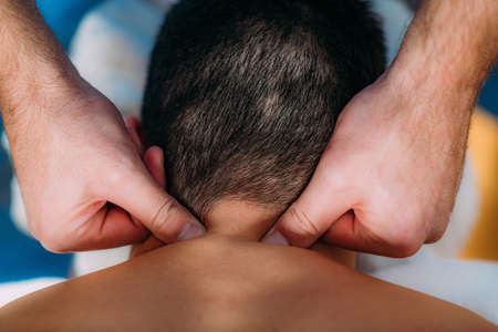 Physiotherapist massaging male patient with injured neck. Sports injury treatment.の写真素材