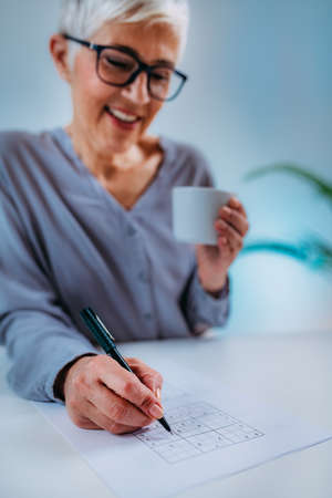 Senior woman solving sudoku puzzle game. Cognitive enhancement therapy for seniors.の写真素材