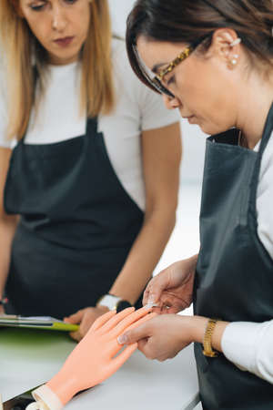Cosmetology education for nail salon manicurist. Practice with mannequin training handの写真素材