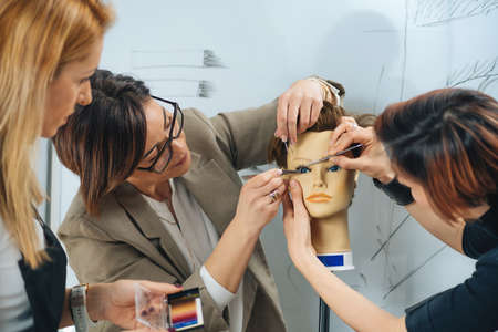 Eyelash Extensions Training Course in Cosmetology Beauty Esthetic Center.  Female students practicing on Silicone Mannequin Headの写真素材