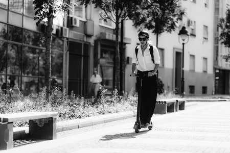 Businesswoman with Backpack Riding a Scooter to Work Down the Street in the City.の写真素材