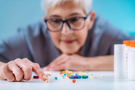 Senior patient counting pills. Medicine non-adherence.の写真素材