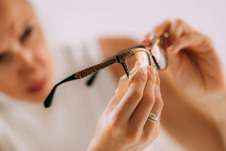 Woman with OCD or obsessive compulsive disorder. Cleaning her eyeglasses.の写真素材