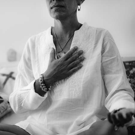 Self-Healing Heart Chakra Meditation. Woman sitting in a lotus position with right hand on heart...