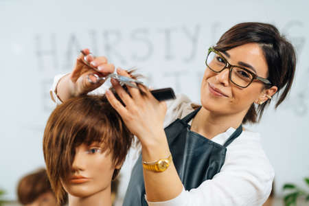 Portrait of female hairstyling educator during training in hair salon, smiling and looking at cameraの写真素材