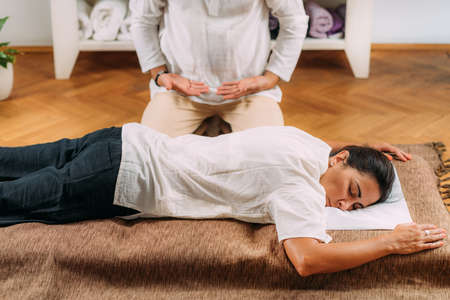 Shiatsu massage meditation. Therapist sitting next to relaxed woman after shiatsu massage treatment.の写真素材