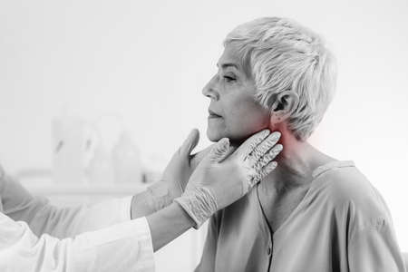 Endocrinology doctor examining a senior woman with thyroid gland disease symptoms