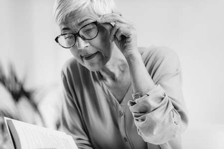 Senior woman a reading book. Vision loss problems.