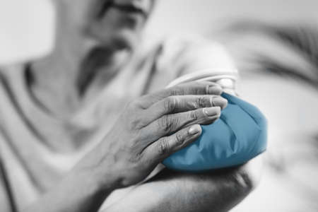 Frozen shoulder. Senior woman holding cold compress, ice bag pack on her painful shoulderの写真素材
