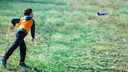 Boy playing with toy glider airplane outdoors on the fieldの写真素材