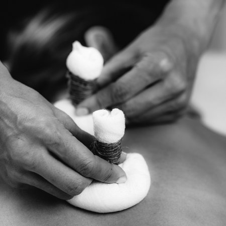 Potli Dry Massage Therapy at Ayurvedic Wellness Center. Female client enjoying relaxing herbal compress massage.の写真素材