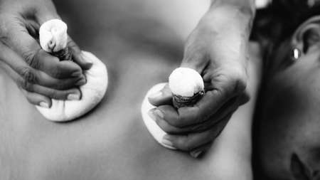 Hands of an Ayurveda Massage therapist pressing herbal bolus bags onto clientâs skinの写真素材