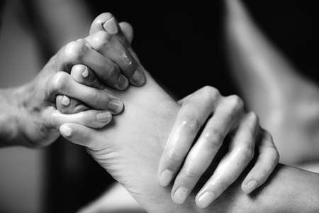 Ayurvedic Foot Massage. Hands of Ayurveda Practitioner massaging female footの写真素材