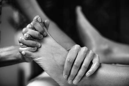 Ayurvedic Foot Massage. Hands of Ayurveda Practitioner massaging female footの写真素材