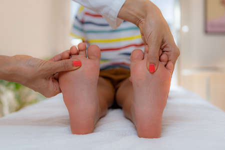Pediatrician examining development boyâs feet on a bed.の写真素材