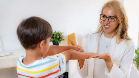 Physical medical exam for children. Physical therapist doing medical exam, boy holding arms raisedの写真素材