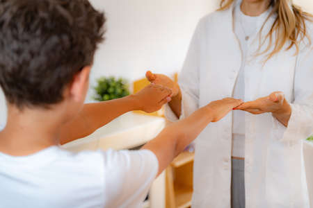 Physical medical exam for children. Physical therapist doing medical exam, boy holding arms raisedの写真素材