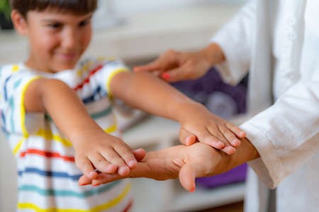 Physical medical exam for children. Physical therapist doing medical exam, boy holding arms raisedの写真素材