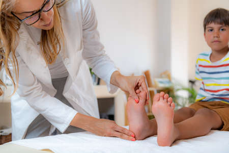 Pediatrician examining development boyâs feet on a bed.の写真素材