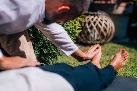 Hands of a Reiki therapist healing and balancing energy points in feet. Energy healing concept