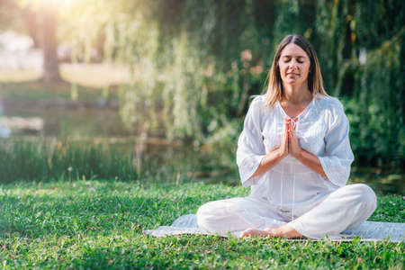 Meditation by the water, hands in prayer position, green background.