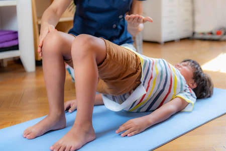 Physical therapy for kids, child doing a bridge with a physical therapist, core strengthening exerciseの写真素材