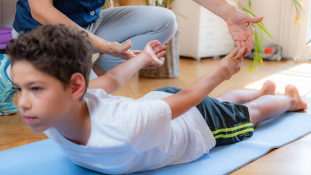 Lower back stretch. Boy exercising with physical therapist.の写真素材