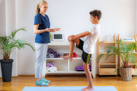 Stretching exercise for children. Boy exercising with physical therapist.