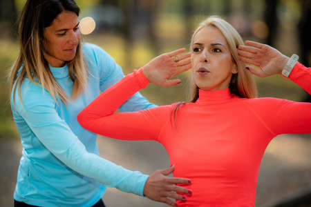 Female Friends Exercising on Outdoor Fitness Equipment in Public Park. Autumn, Fall.の写真素材
