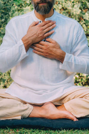 Reiki spiritual self-treatment healing session. Man holding hands above the heart chakra.の写真素材