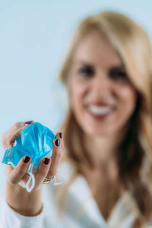 Smiling woman taking off and throwing away the face mask, celebrating the end of covid-19...
