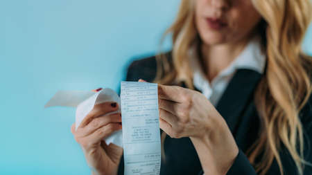 Worried business woman holding bills, inflation increasing costs.の写真素材
