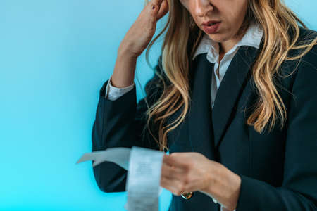 Worried business woman holding bills, inflation increasing costs.の写真素材