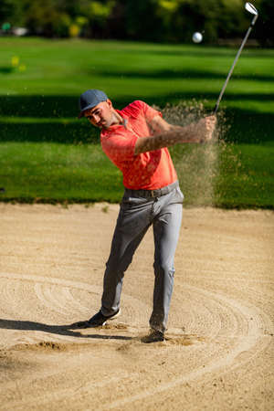 Golfing shot from sand, professional golf player playing from a sand bunker, golf ball in the airの写真素材