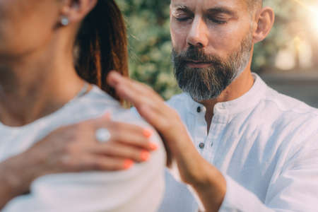Reiki Lesson. Reiki instructor with hands over shoulders of the course attendee, transferring...