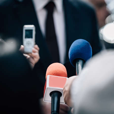 Media interview, a politician talking, reporters holding microphonesの写真素材