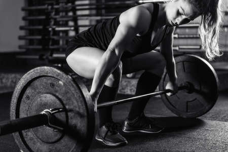 Cross training. Female athlete lifting heavy barbells