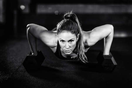 Cross training. Young woman exercising with dumbbells
