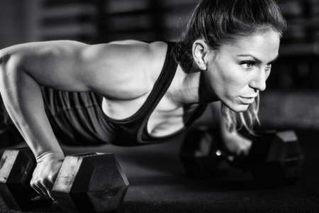 Cross training. Young woman exercising with dumbbellsの写真素材