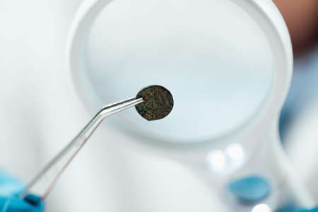 Professional coin expert examining ancient coins with magnifying glass