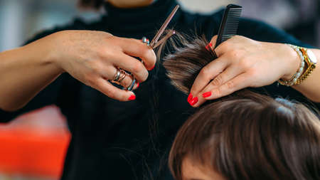 Hairdresser's hands with scissors cutting boys hair in hair salonの写真素材
