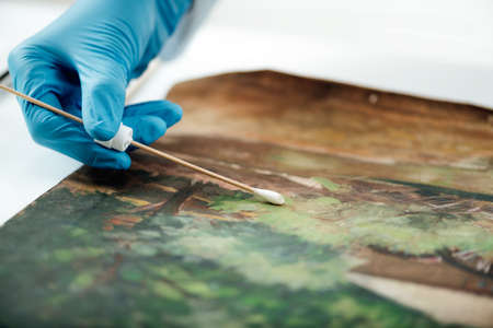 Oil painting cleaning, female conservator removing dirt from an old oil paintingの写真素材